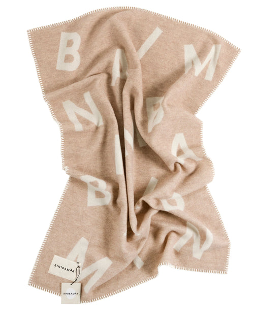 Alphabet Merino Biniblanket – Couverture pour berceau – BINIBAMBA : couverture drapée sur fond clair.