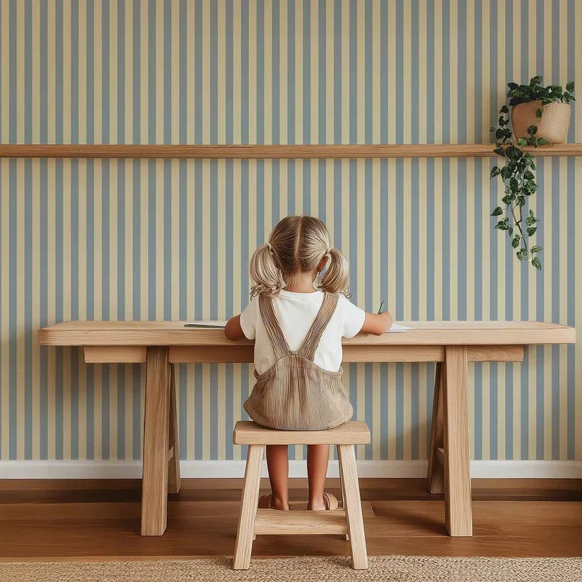 Smalle Strepen Lichtblauw – Atelier Chien : papier peint derrière un enfant assis à une table en bois.