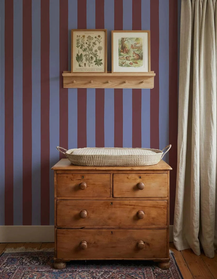 Brede Strepen Bordeaux Blauw – Atelier Chien: wallpaper behind a wooden changing table with a changing basket.