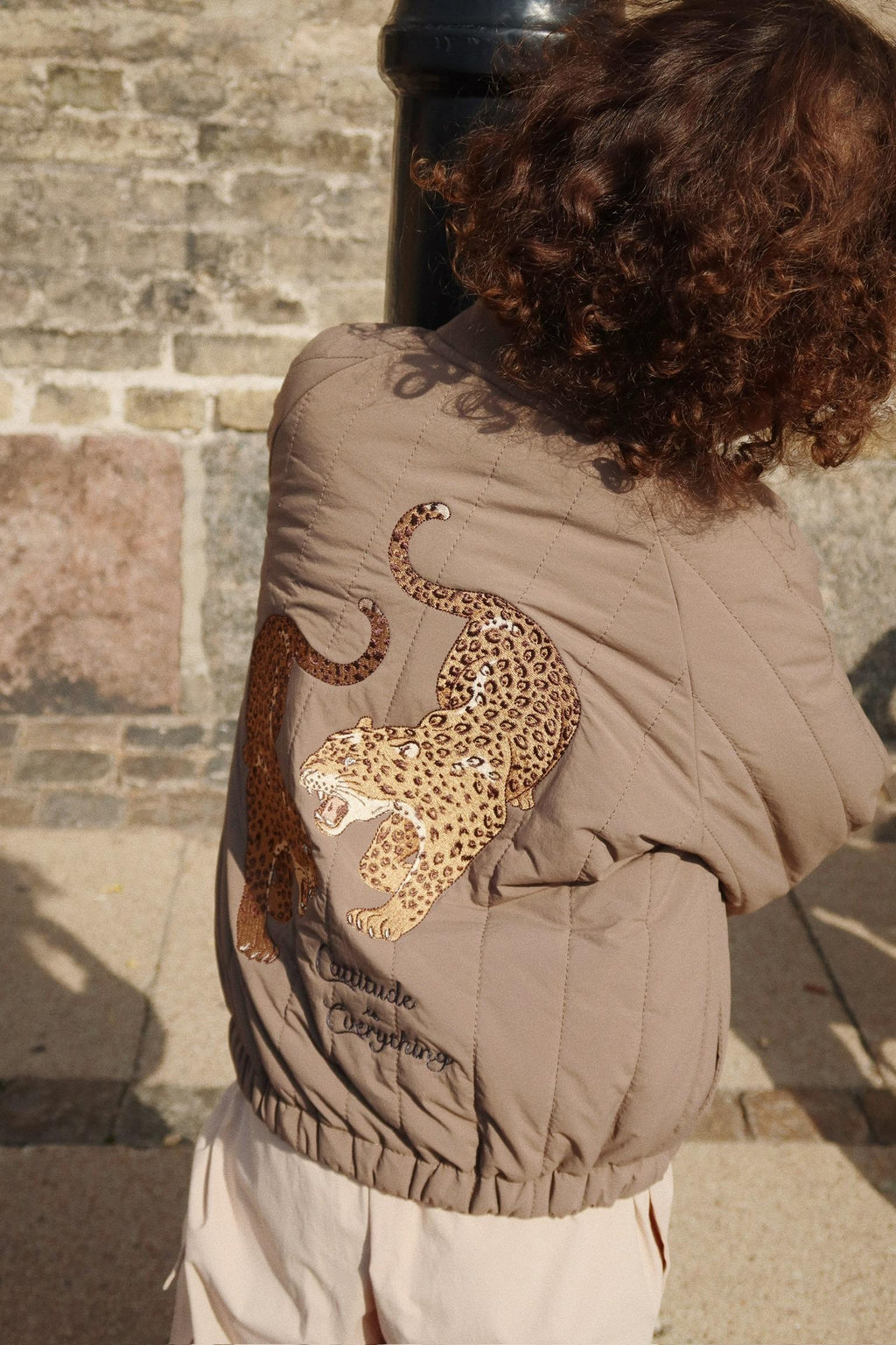 Thermo jacket Juno Bomber – Walnut – Konges Sløjd: detail of the leopard artwork on the back of the bomber jacket being worn.