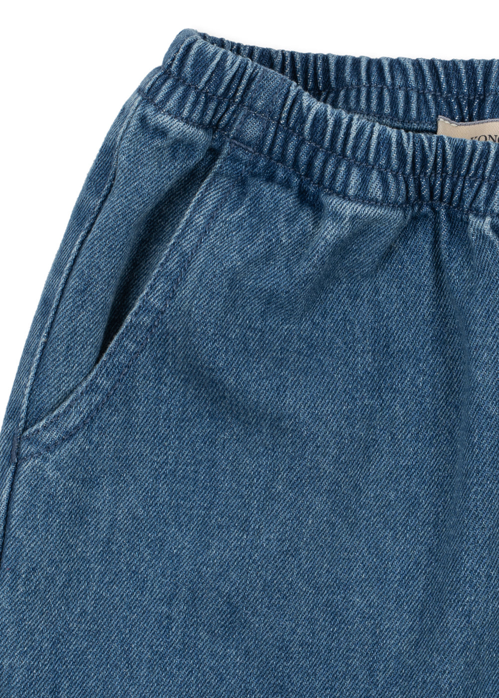 Denim broek Magot – Denim Blue – Konges Sløjd: detail van de elastische tailleband en steekzak van de denimbroek.